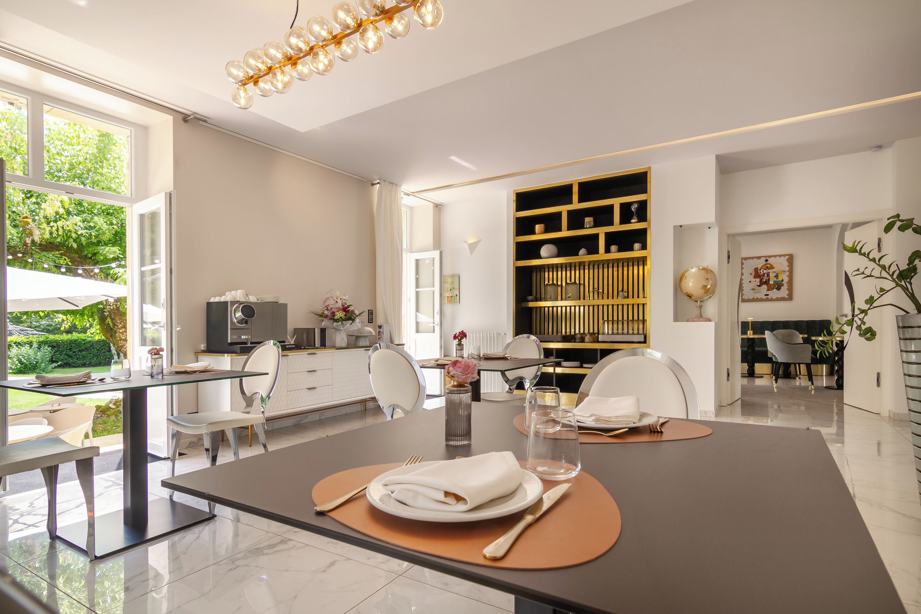 A modern dining area with a glass table, white chairs, and a central island with a globe and decorative items.