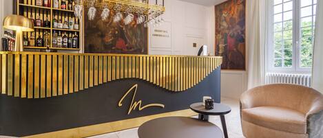 A bar area with a black and gold design, a sofa, a chair, and a large window with a view.