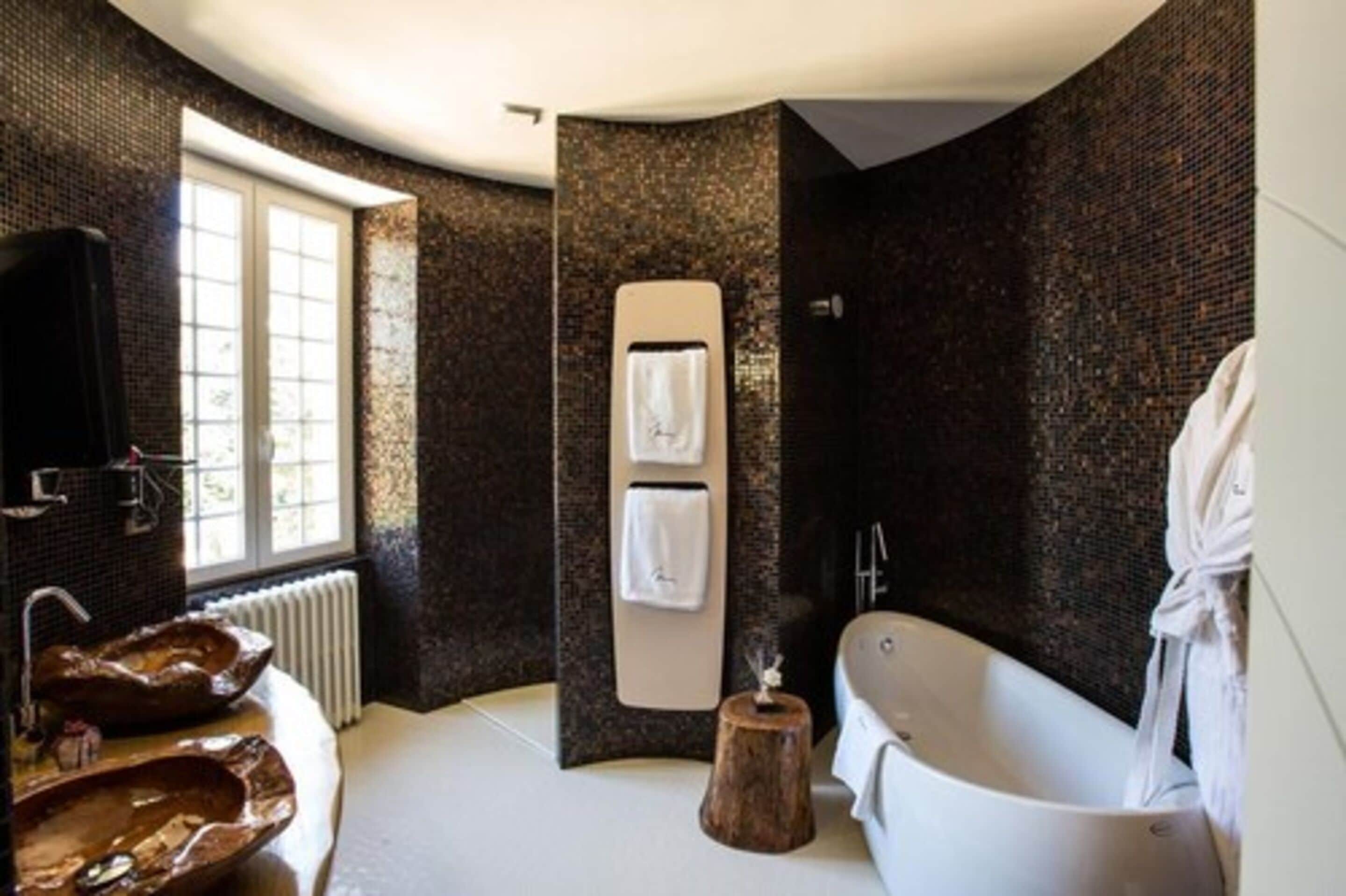 Une salle de bain moderne avec une baignoire sur pieds, une grande fenêtre et un revêtement mural texturé au design original.