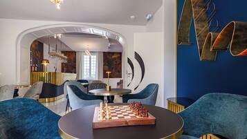 A modern interior with a round table, chessboard, and blue upholstered chairs.
