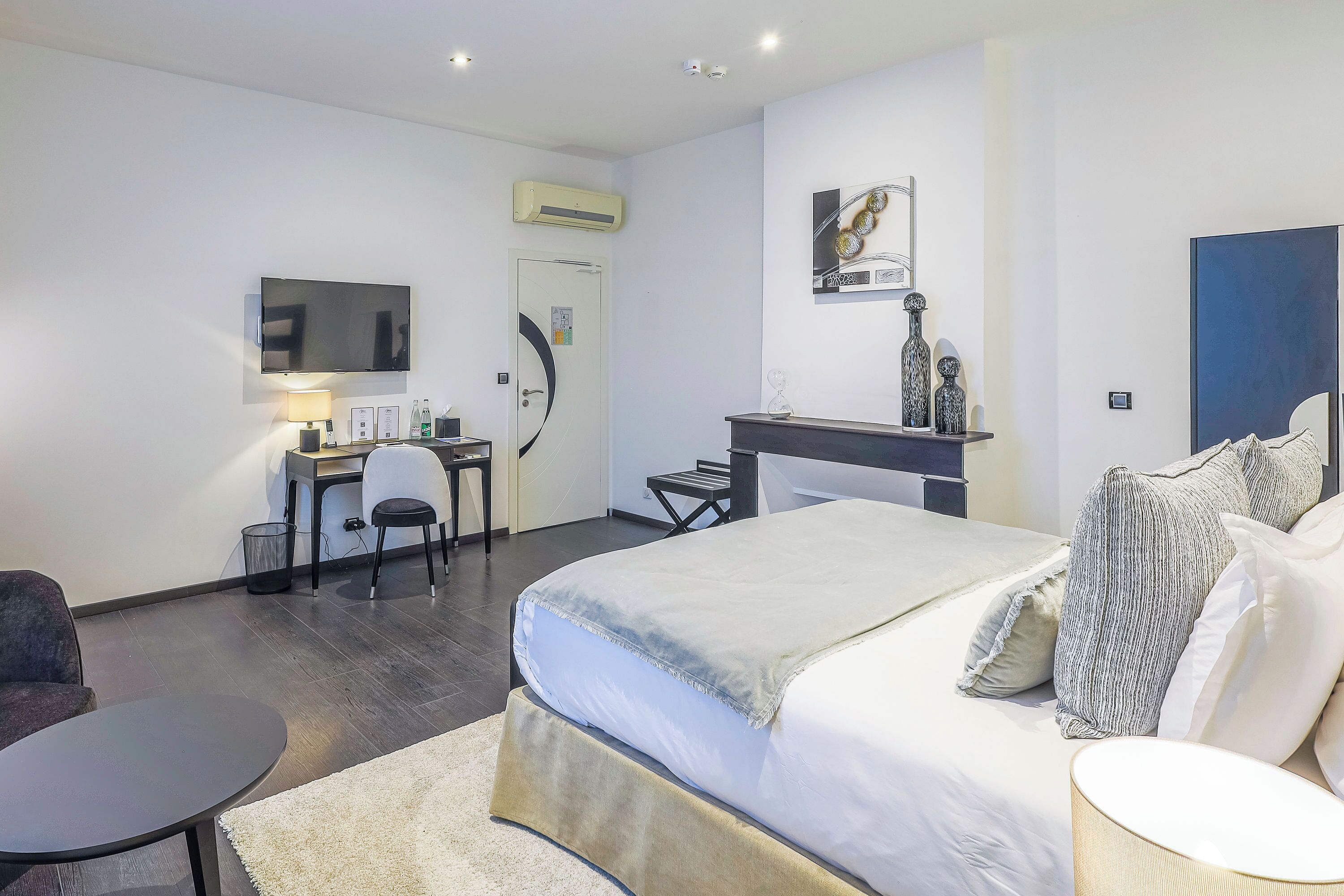 Una habitación de hotel moderna con cama, escritorio, silla y televisor de pantalla plana.