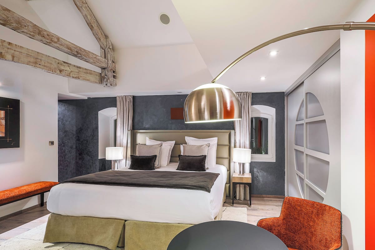 A modern hotel room with a large bed, a desk, and a chair.