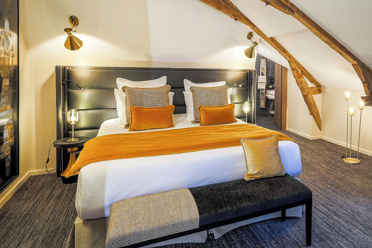 A spacious bedroom with a large bed, a bench, and a nightstand.