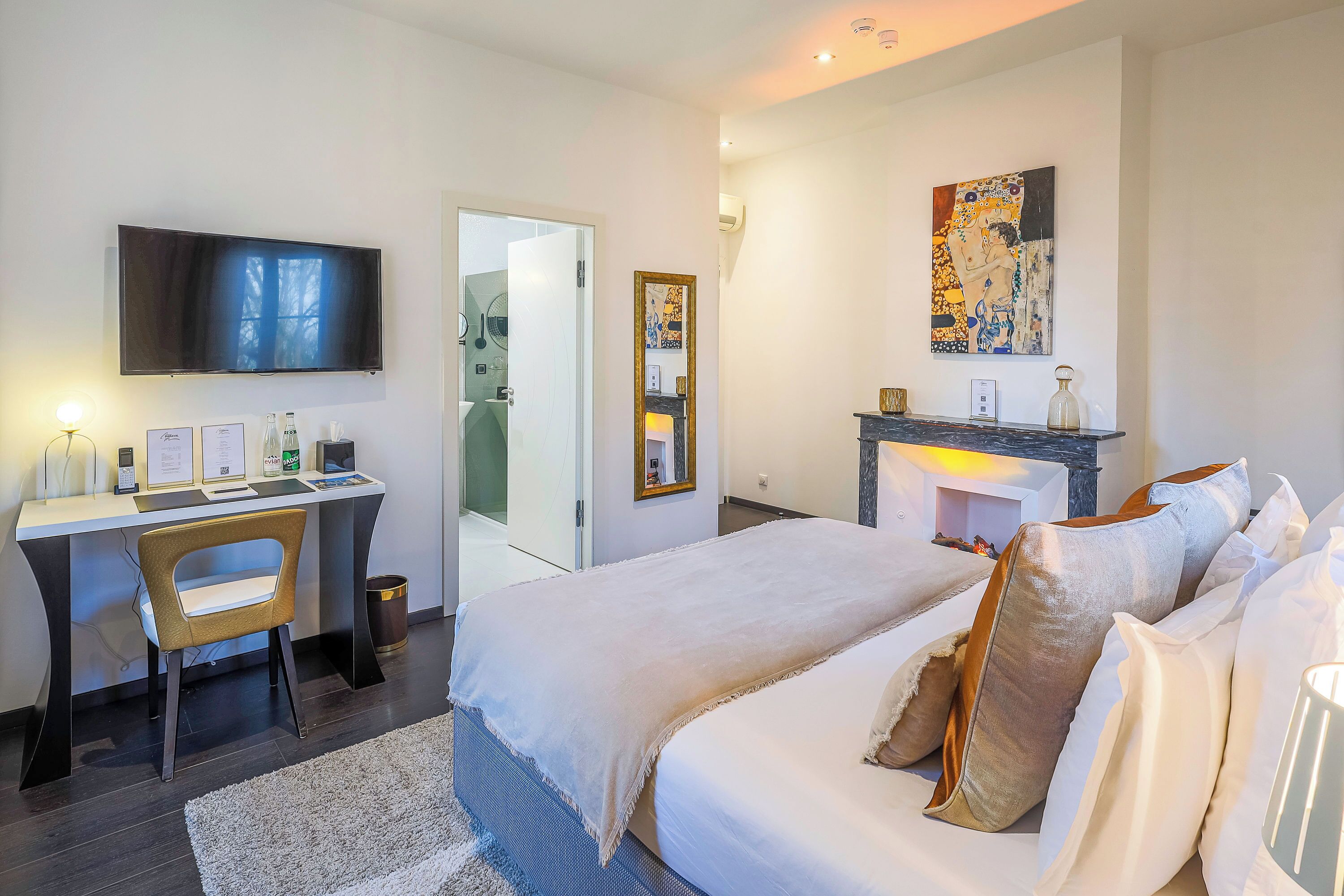 A modern hotel room with a bed, desk, and TV.