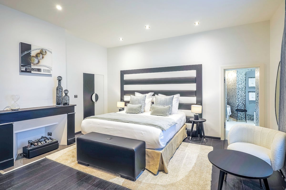 A modern bedroom with a large bed, bedside tables, a desk, and a chair.
