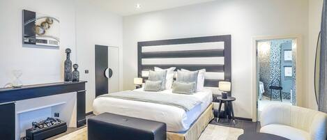 Un dormitorio moderno con una cama grande, mesitas de noche, un escritorio y una silla.