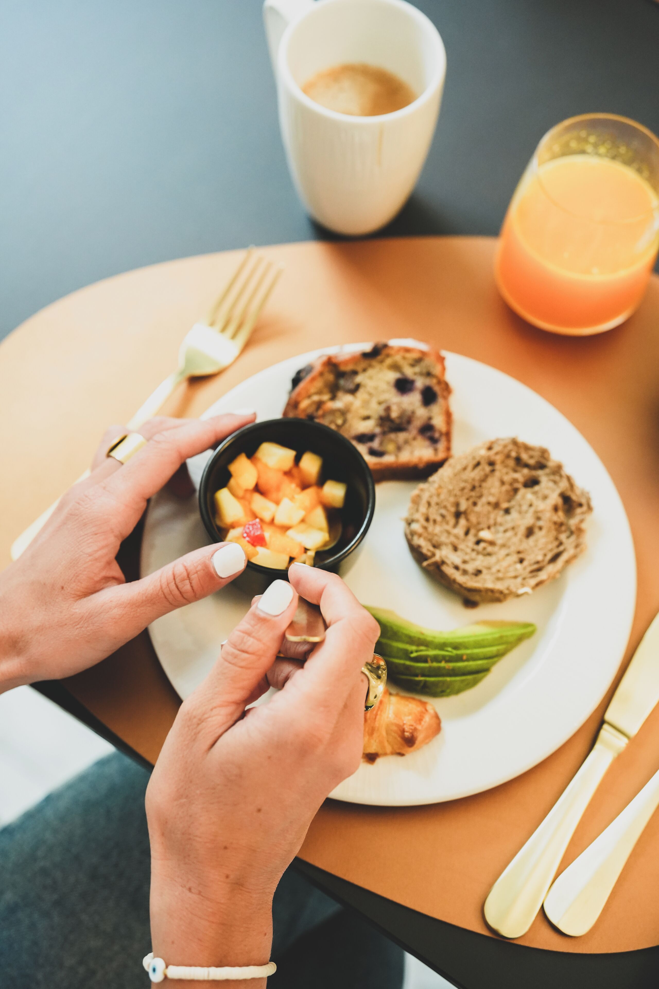 Une table mise pour le petit-déjeuner, avec une assiette de nourriture, une tasse de café et un verre de jus d’orange.