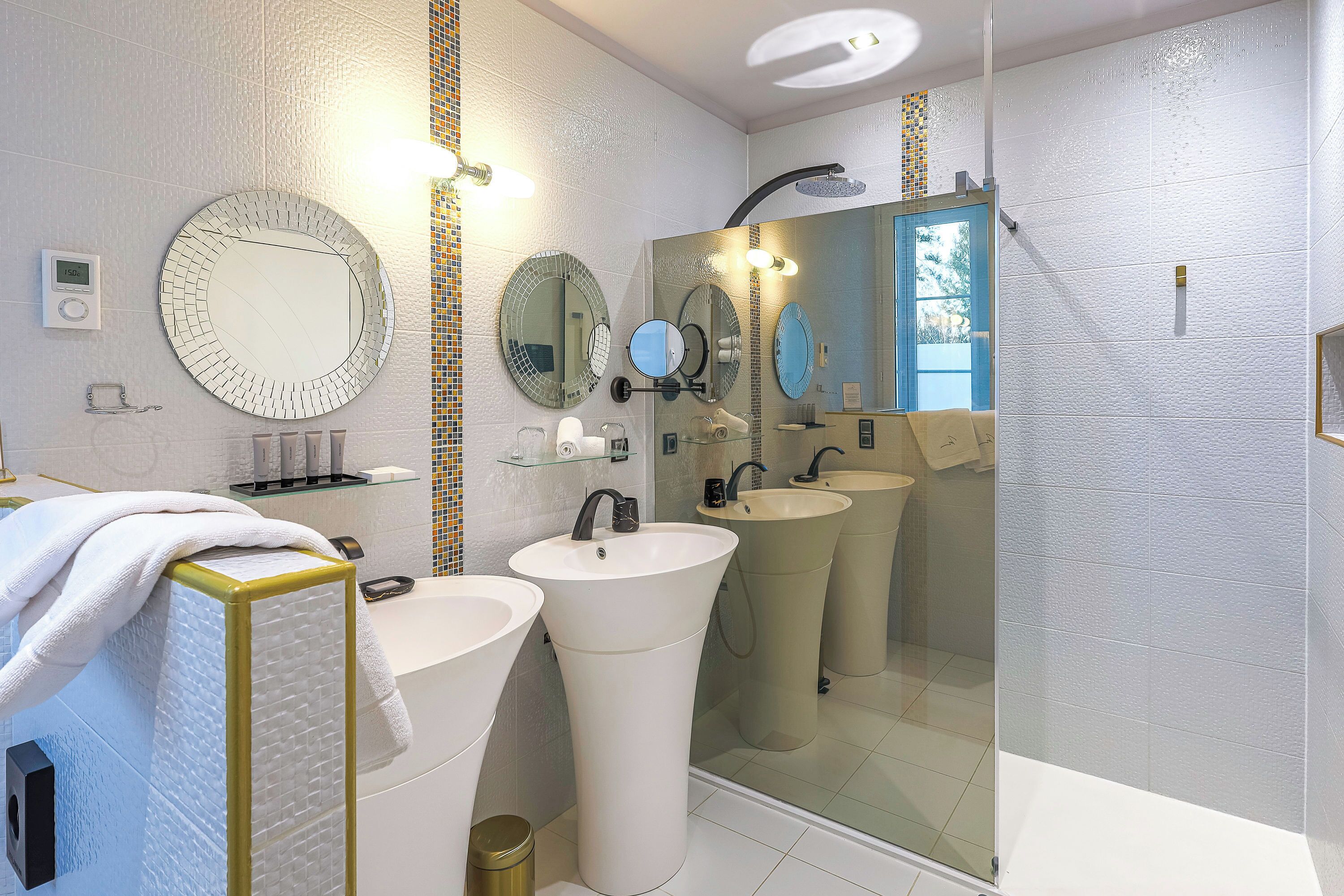 A modern bathroom with two sinks, a large mirror, and a shower.