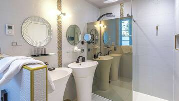 A modern bathroom with two sinks, a large mirror, and a shower.