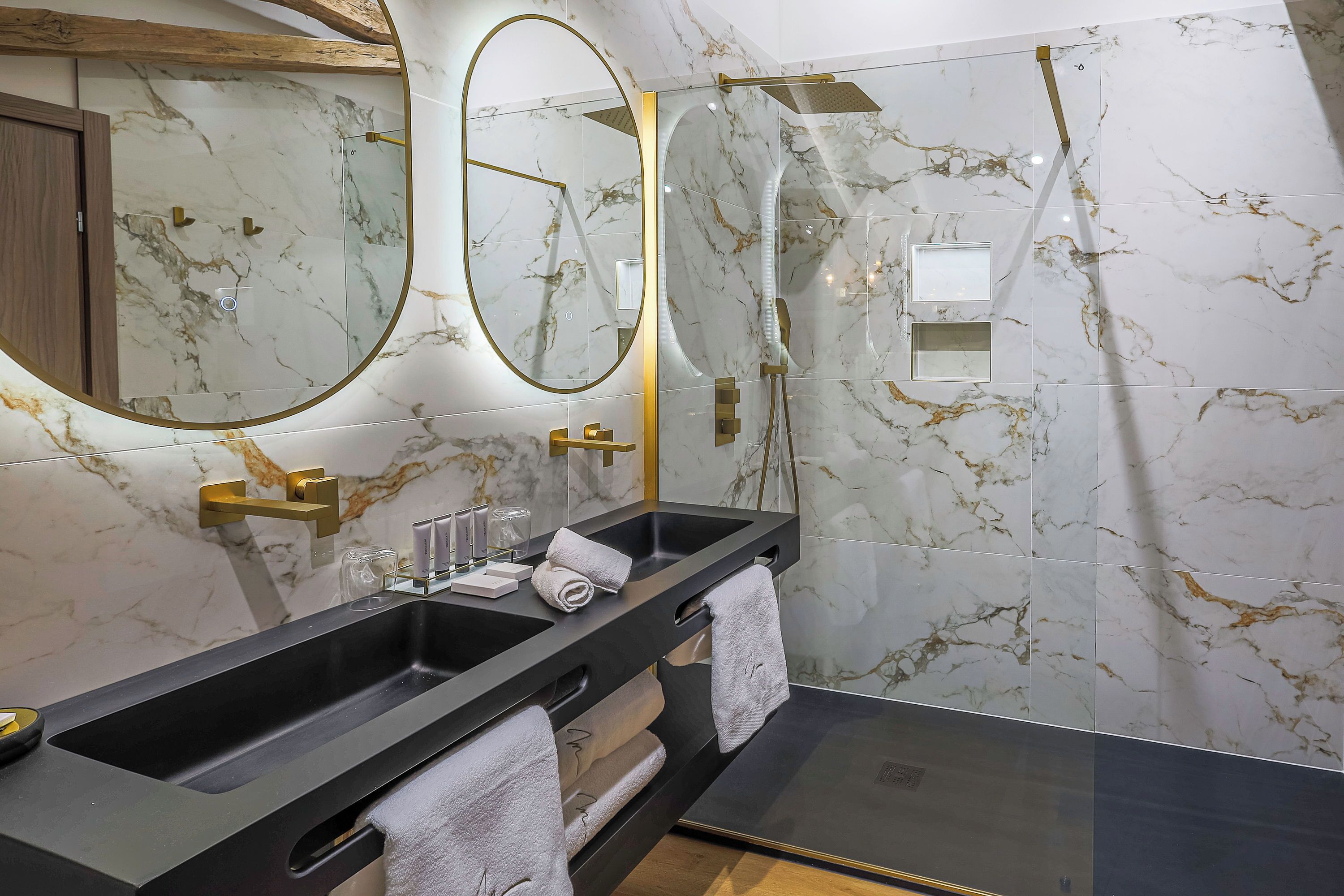 A modern bathroom with a large mirror, two sinks, and a glass shower enclosure.
