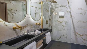 A modern bathroom with a large mirror, two sinks, and a glass shower enclosure.