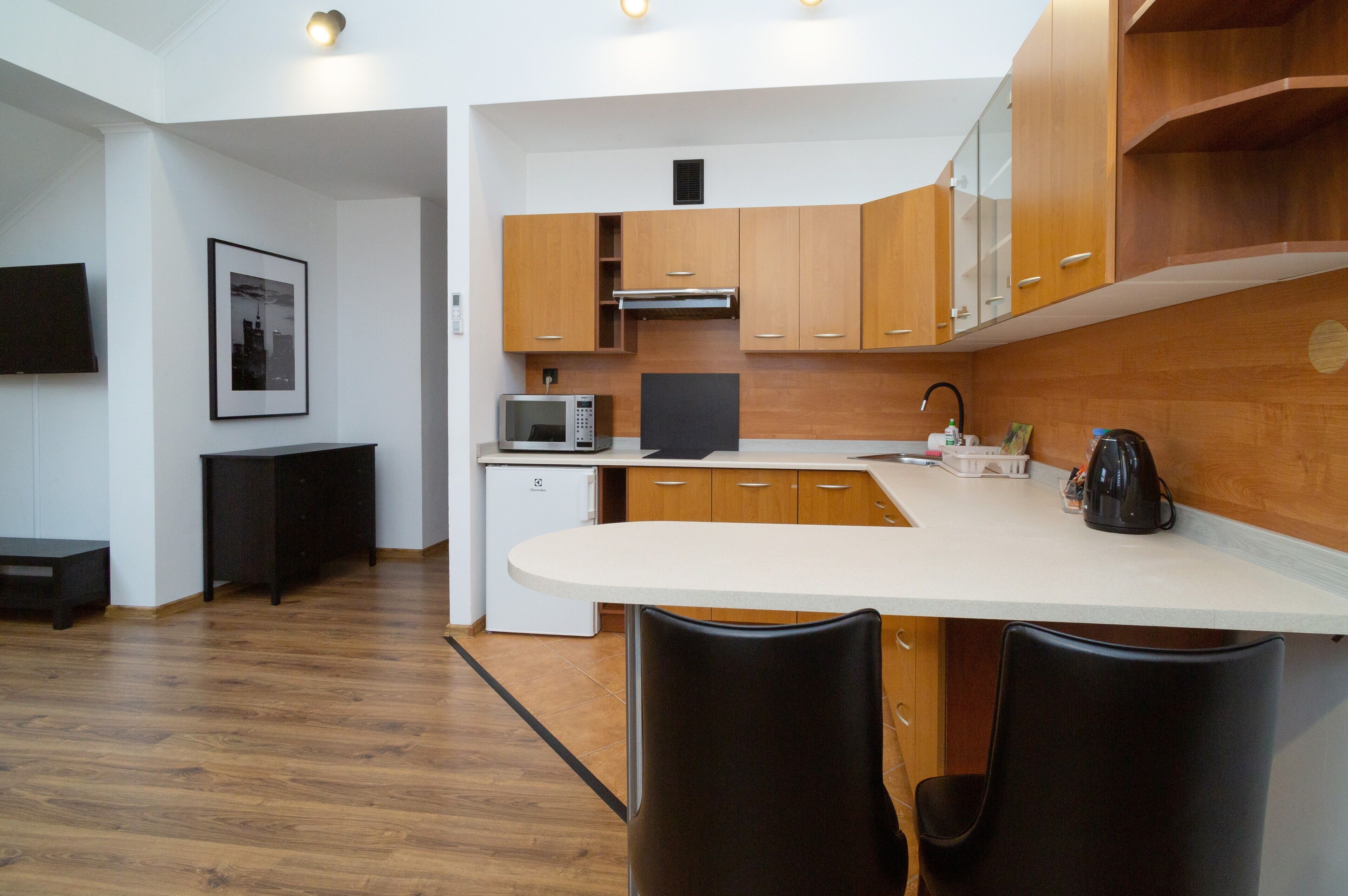 A modern kitchen with wooden cabinets, a white countertop, and a black chair.