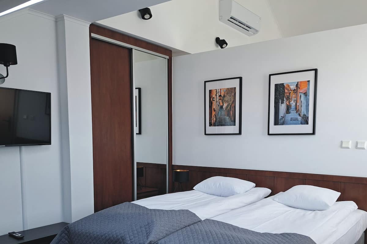 Une chambre d’hôtel avec un lit, une télévision, un miroir et deux tableaux encadrés au mur.
