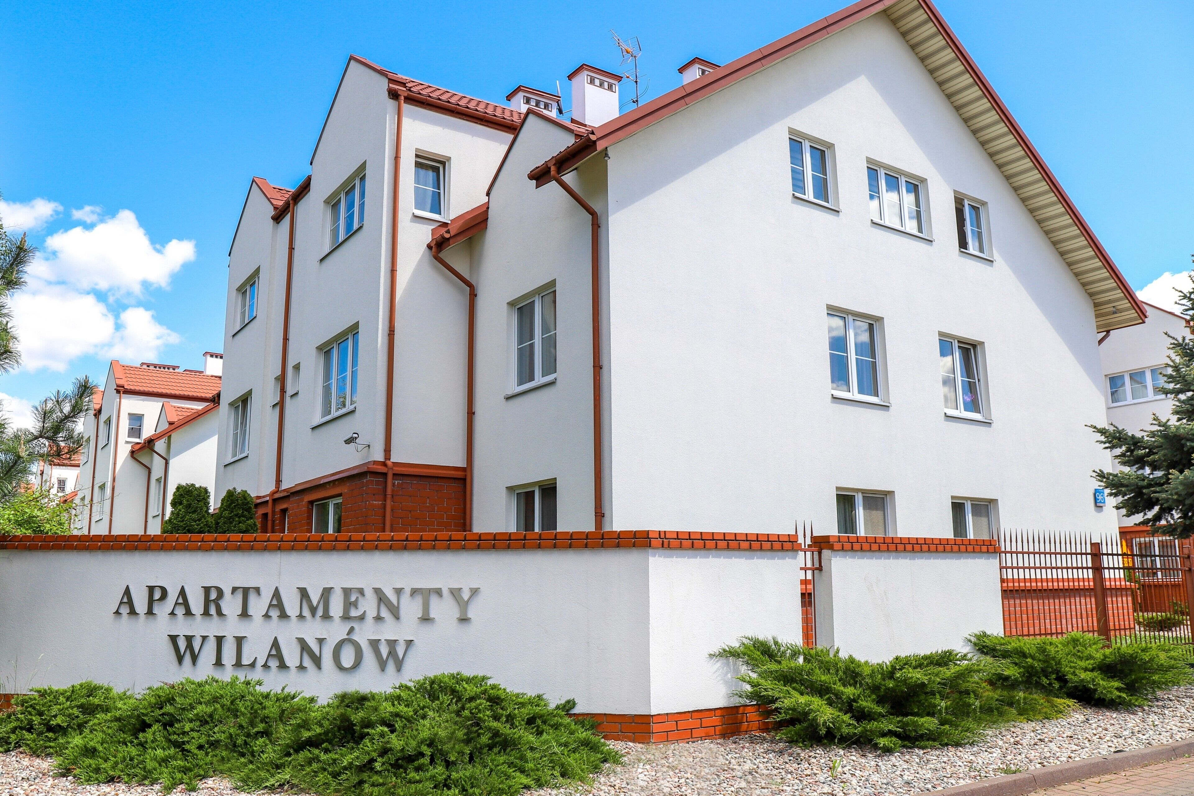 En flervåningsbyggnad med en skylt som visar texten ”APARTMENTY WILANÓW”.