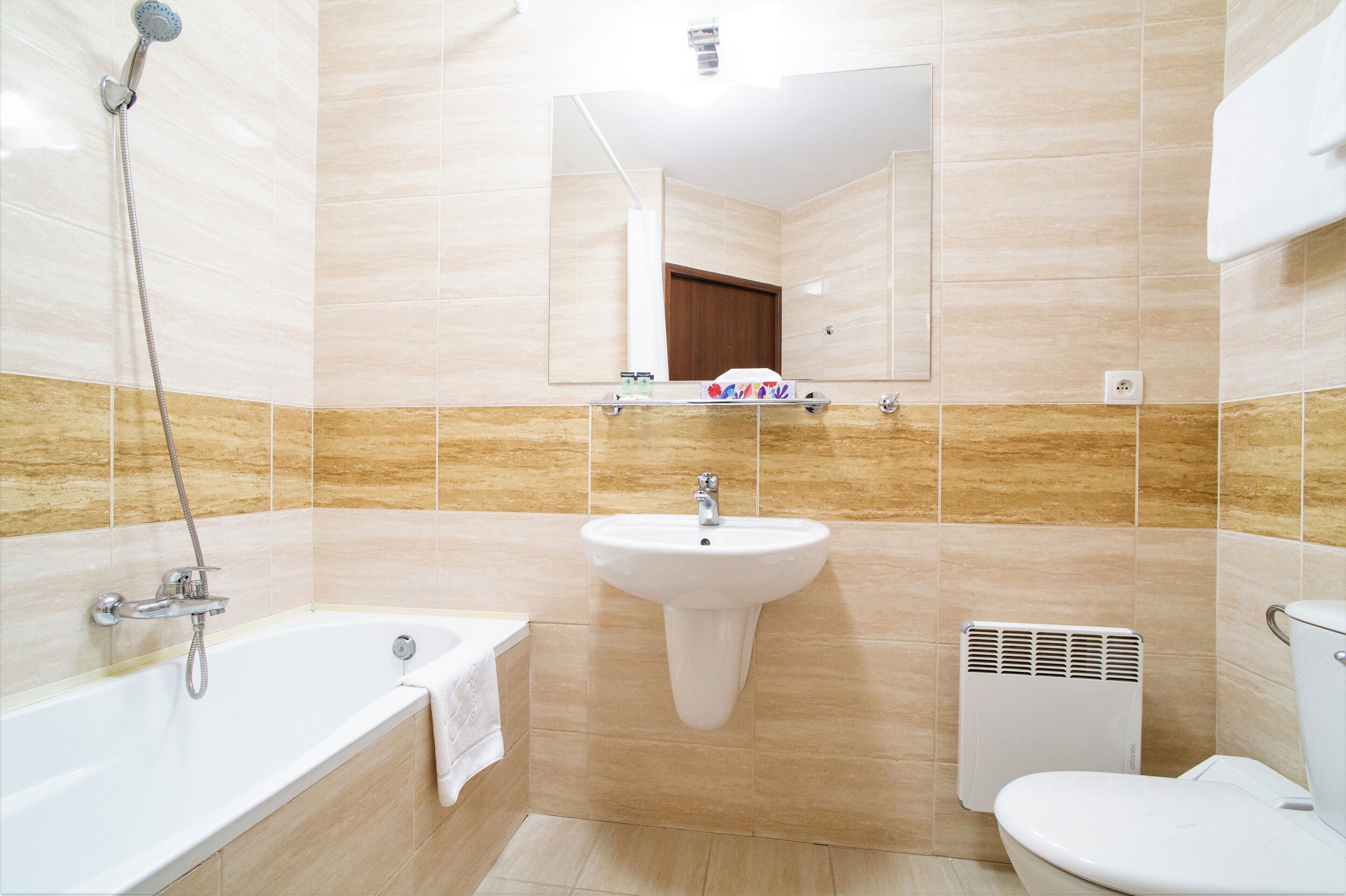 A bathroom with a bathtub, sink, toilet, and a mirror above the sink.