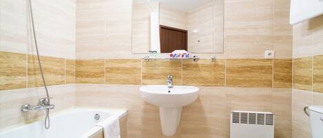 A bathroom with a bathtub, sink, toilet, and a mirror above the sink.