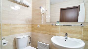 A bathroom with a toilet, a sink, a towel rack, a hairdryer, and a mirror.