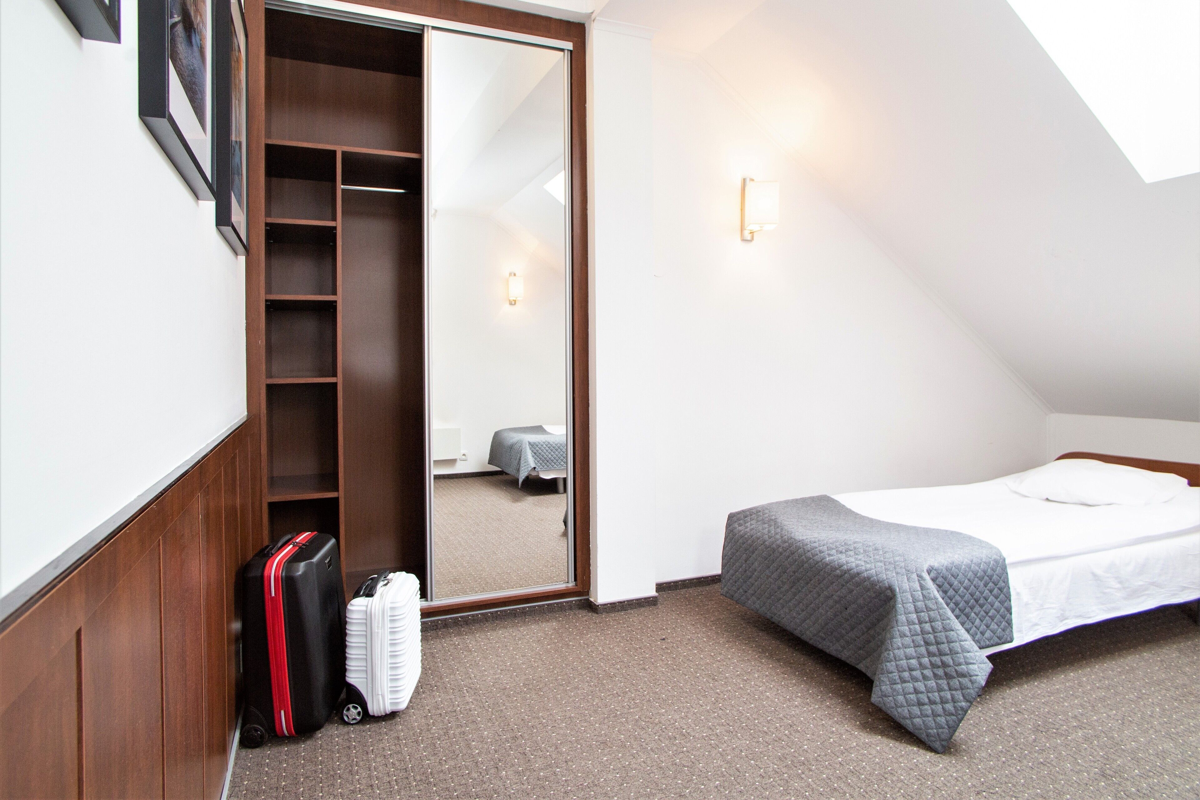 Una habitación pequeña con una cama, un armario y una maleta.