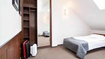 Una habitación pequeña con una cama, un armario y una maleta.