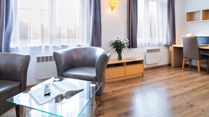 Un salon moderne avec une table basse en verre, des fauteuils en cuir, un bureau en bois et un ordinateur.