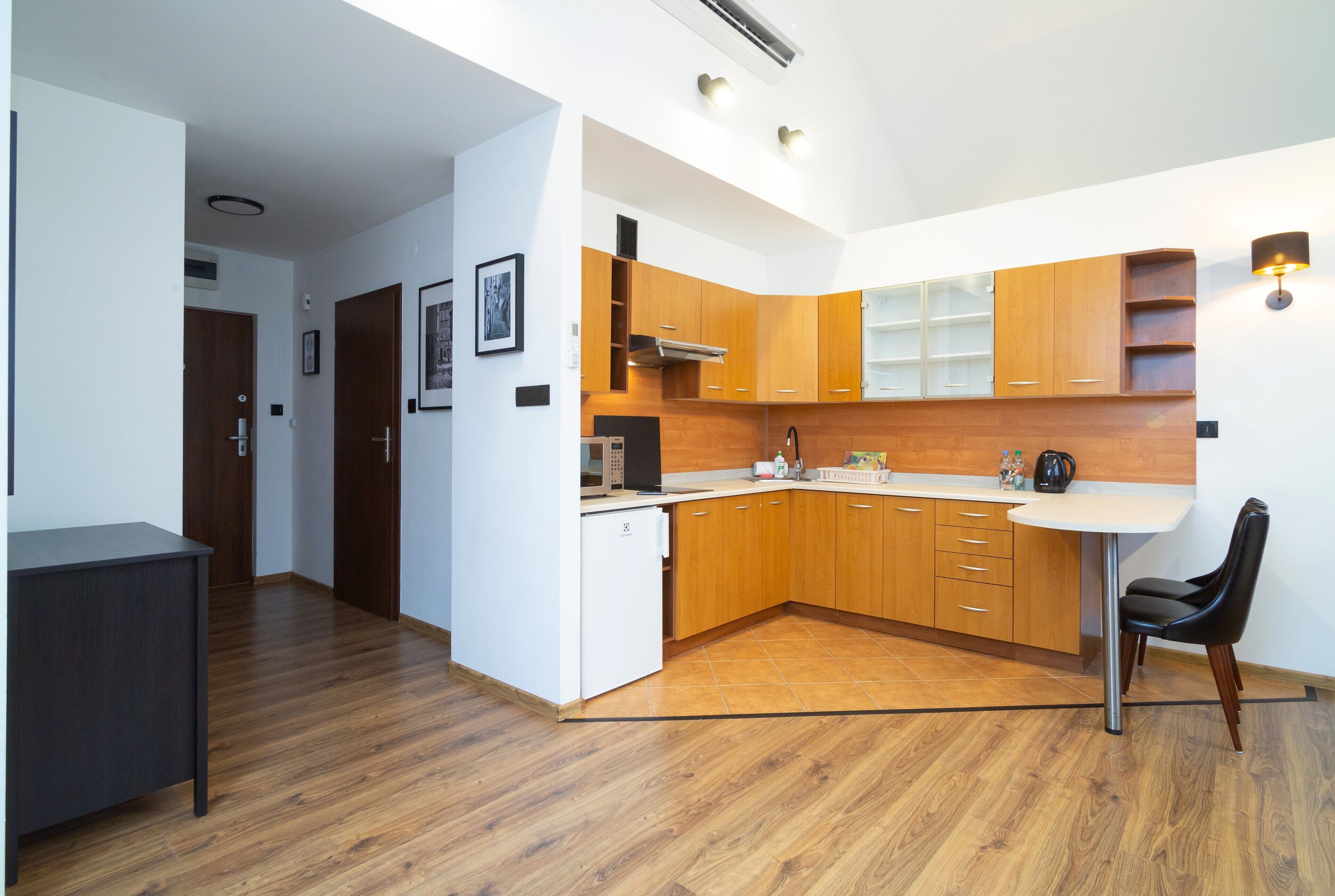 A modern kitchen with wooden cabinets, a white countertop, and a black chair.