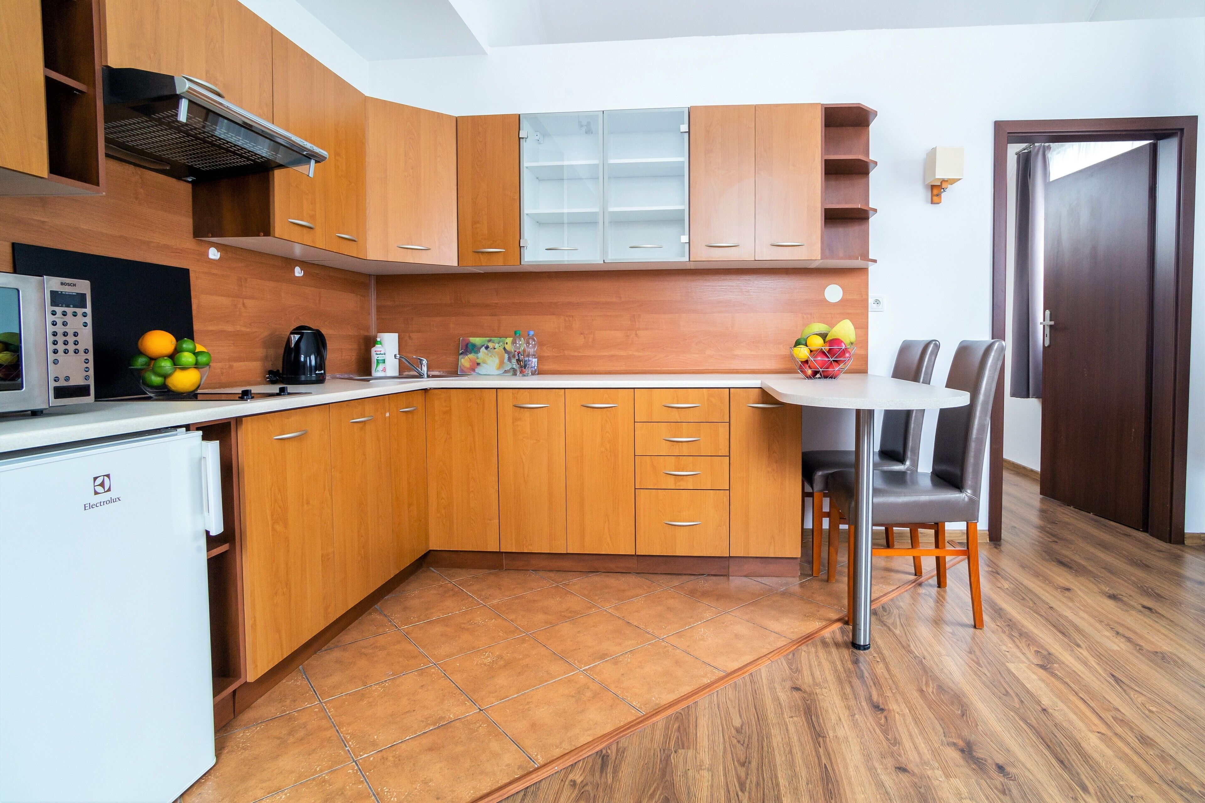 A compact kitchen with wooden cabinets, a built-in microwave, and a small refrigerator.