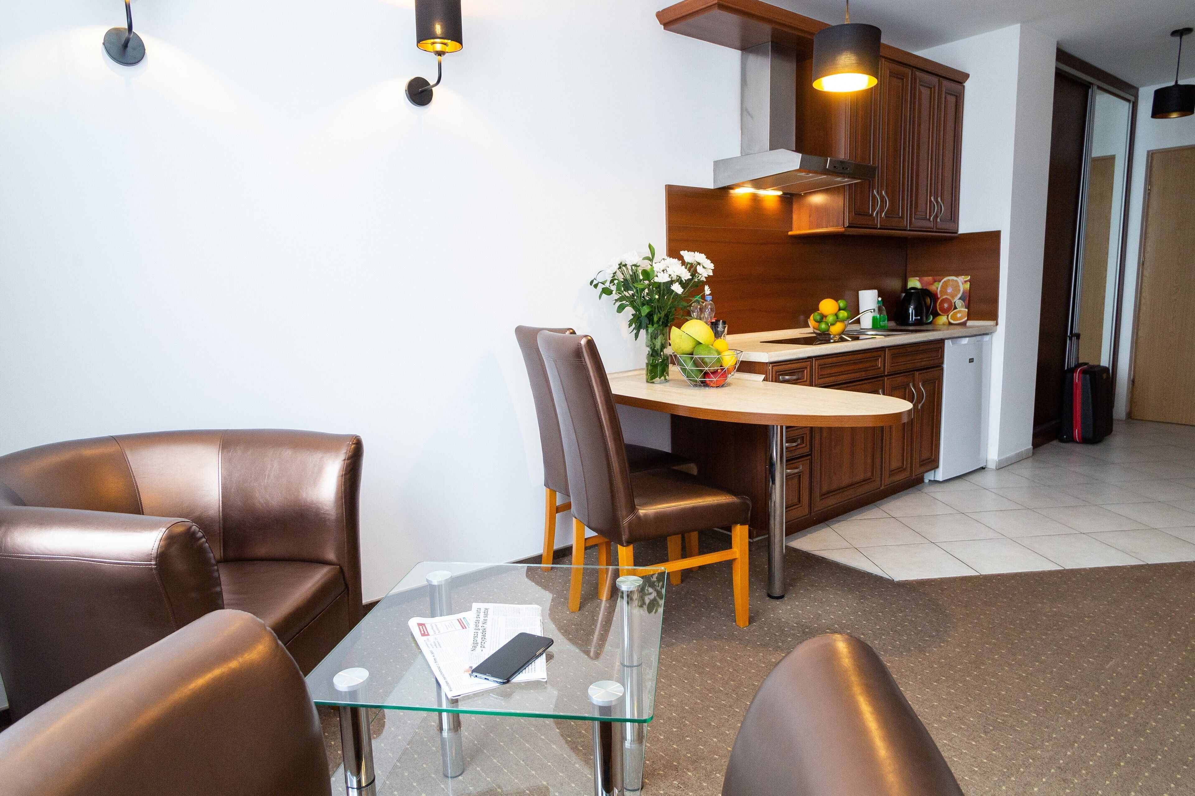 A modern kitchen with wooden cabinets, a stainless steel range hood, and a small island with a coffee maker and fruit bowl.