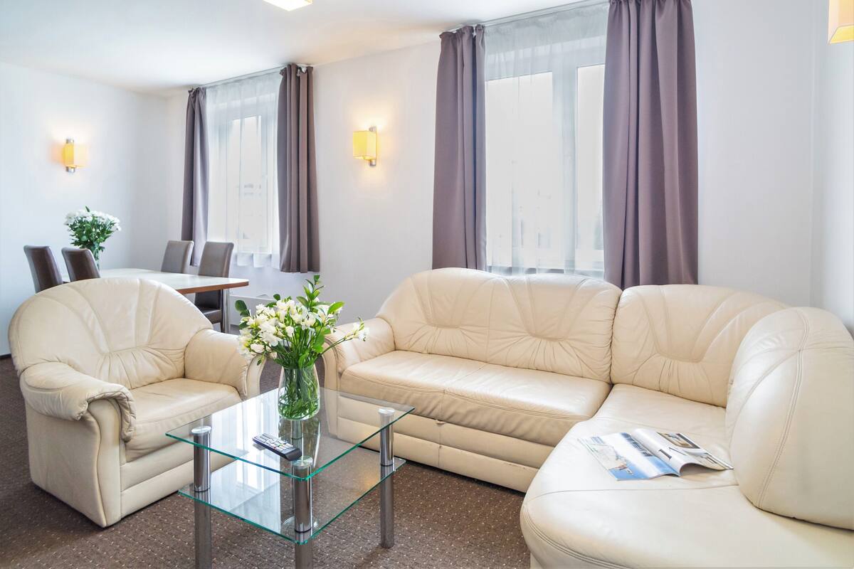 Un salon moderne avec un canapé beige, une table basse en verre et un coin repas comprenant une table et des chaises.
