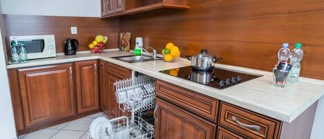 A modern kitchen with wooden cabinets, a built-in dishwasher, a microwave, a sink, and various kitchen appliances.
