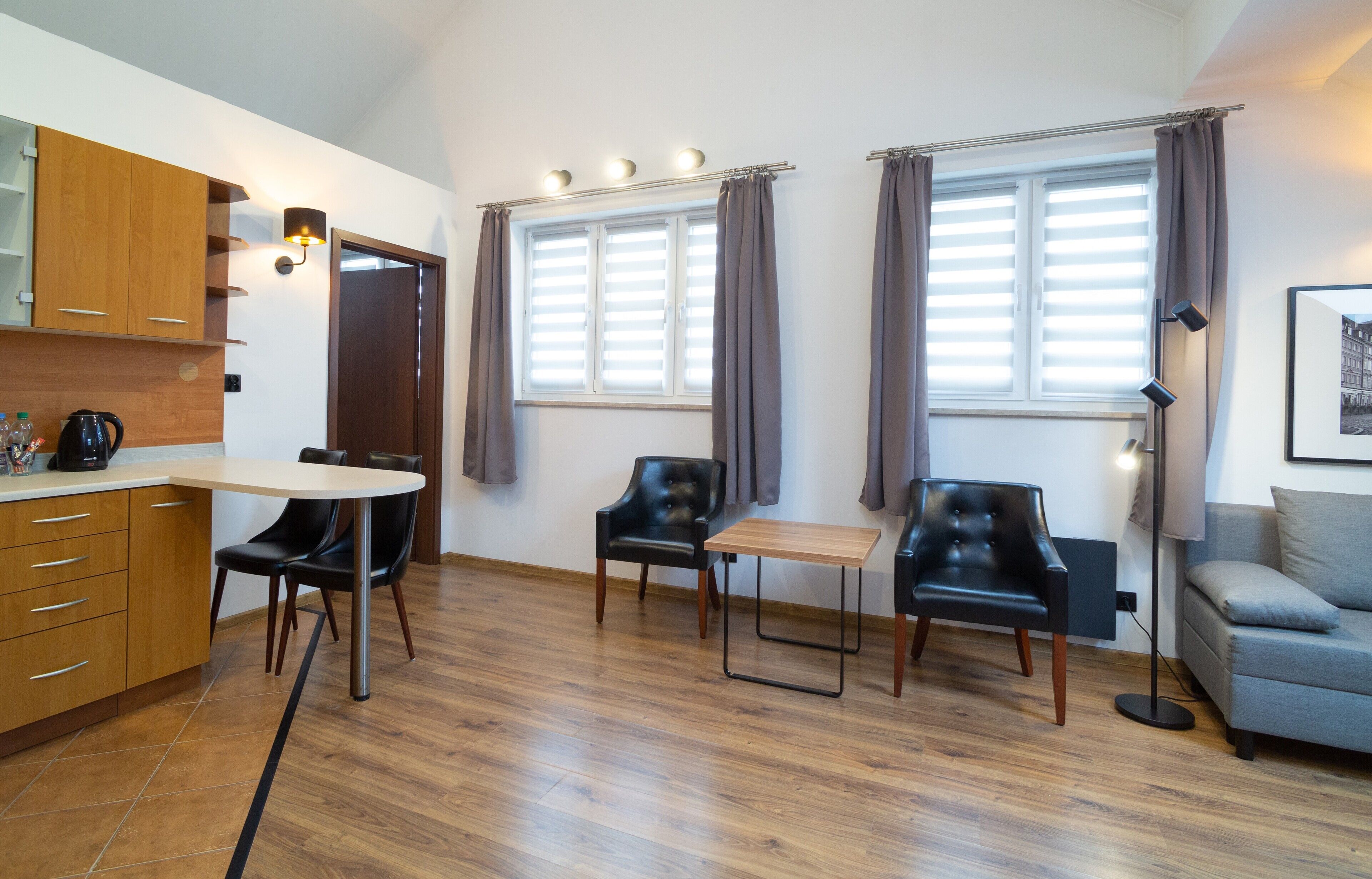 A compact living space with a kitchenette, two chairs, a sofa, and a dining table.