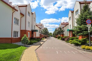 Egy lakóövezetben található utca, mindkét oldalán házakkal, tiszta égbolttal és egy „parkolás tilos” táblával.
