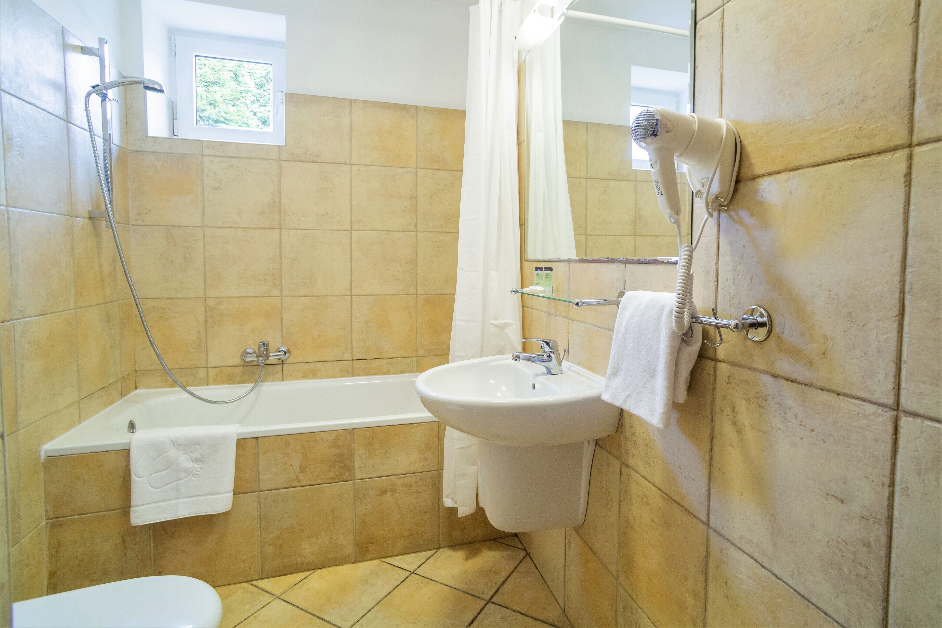 A bathroom with a bathtub, a sink, a hairdryer, and a showerhead.