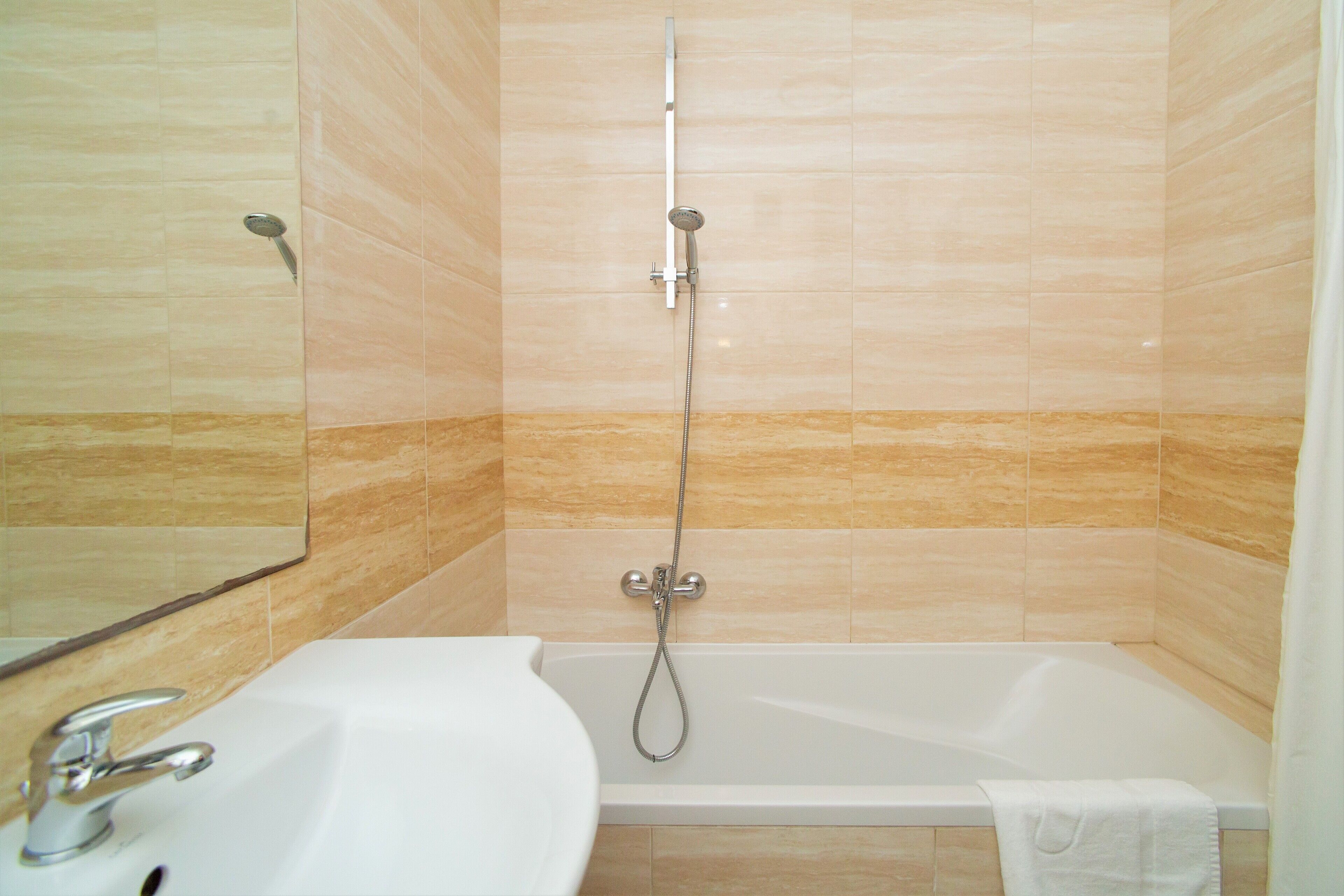 Ein Badezimmer mit einem weißen Waschbecken, einer Badewanne und einer Duschbrause.