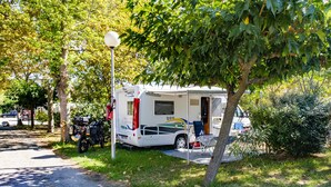 A recreational vehicle parked in a grassy area with a tree nearby. - Camping de Pujol (Argelès-sur-Mer)