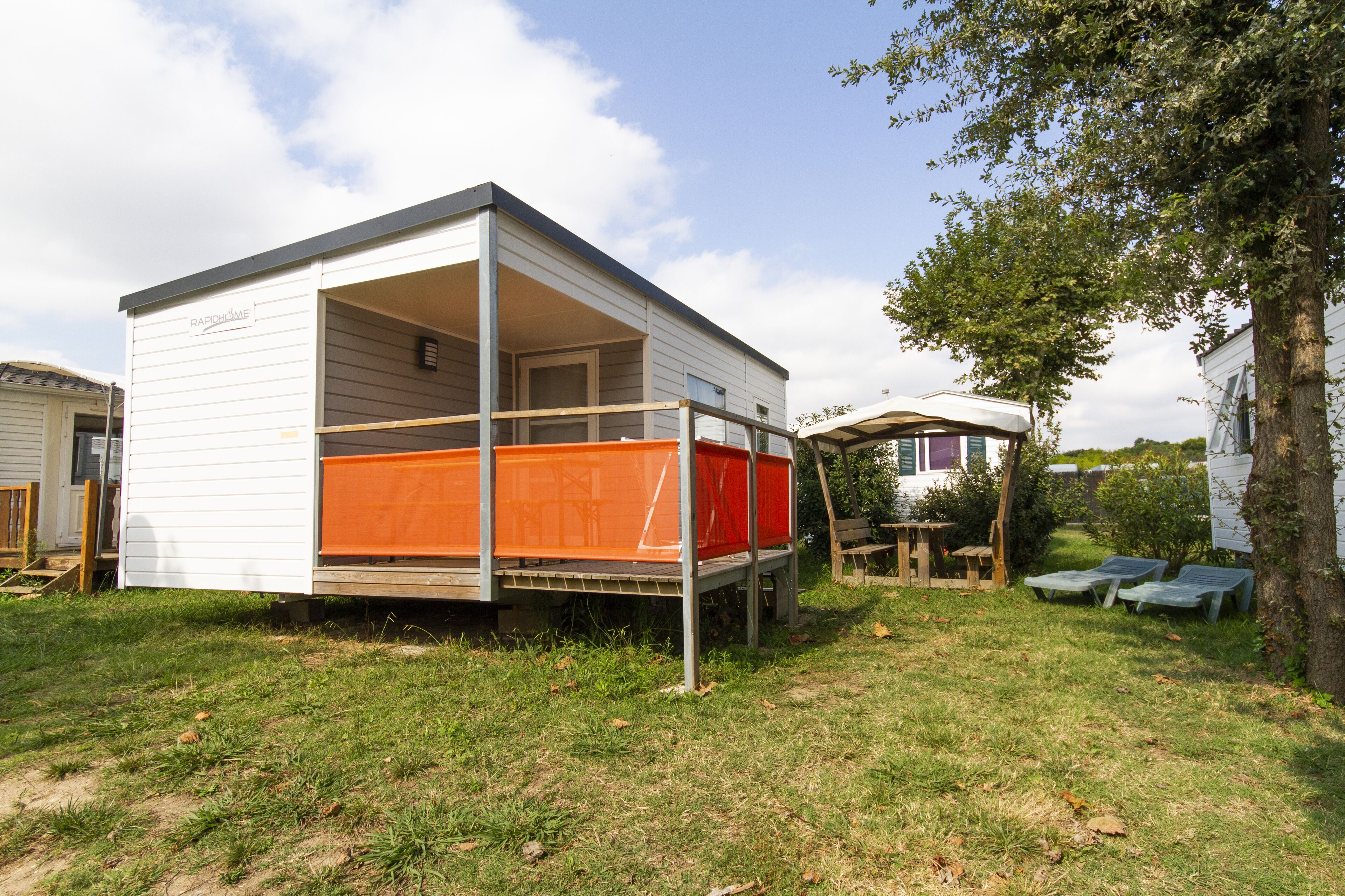 A mobile home with an open porch and a covered outdoor seating area.