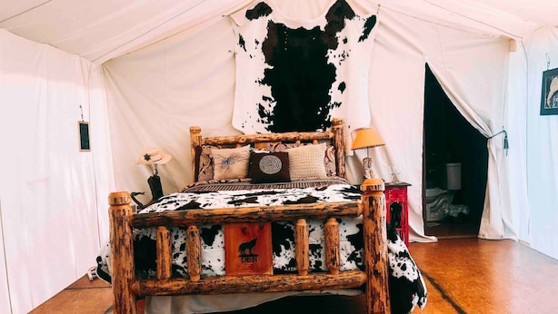 Una cama con tablero de cabecera de cuero de vaca, estructura de madera y colchón de cuero de vaca.
