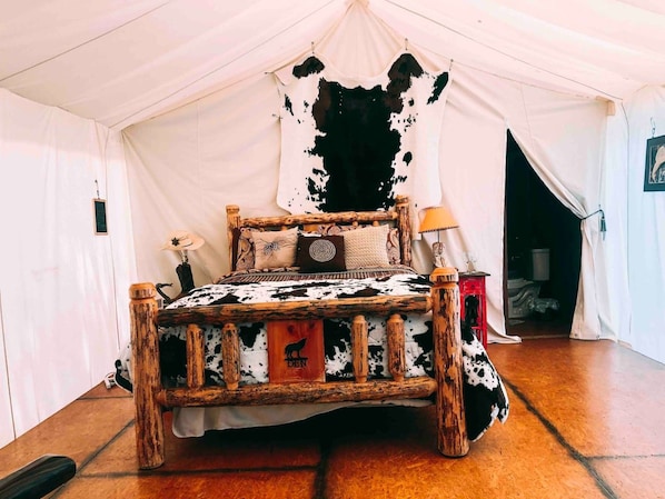 Una cama con tablero de cabecera de cuero de vaca, estructura de madera y colchón de cuero de vaca.