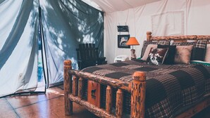 Una habitación con carpa, una cama de madera, una lámpara y un cuadro en la pared.