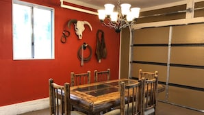 Un comedor con una mesa y sillas de madera, una pared roja y una puerta de garaje.
