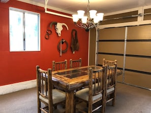 Un comedor con una mesa y sillas de madera, una pared roja y una puerta de garaje.