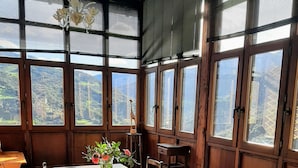 A dining area with a large table, chairs, a vase with flowers, and a view of a mountainous landscape through large windows. - Richard and Suzanne Aparment cozy with an incredible views, quiet Valley. (Pico de Europa Cantabri)