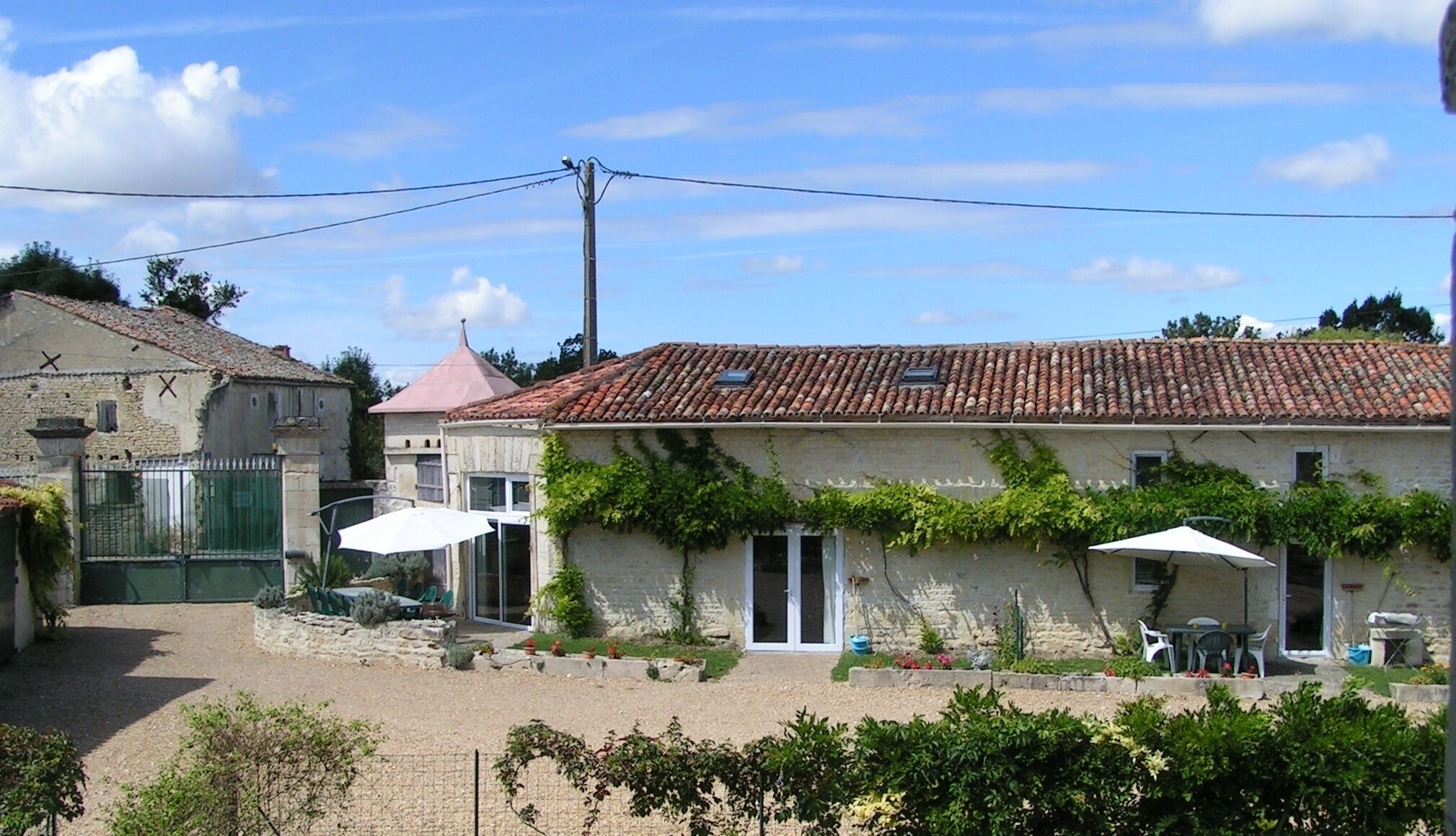 A rustic building with a tiled roof, a gated entrance, and outdoor seating.