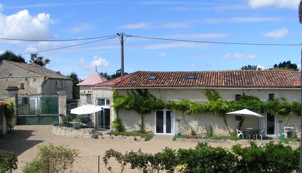A rustic building with a tiled roof, a gated entrance, and outdoor seating.