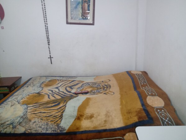A bed with a tiger print bedspread, a small framed picture on the wall, and a cross hanging on the wall.