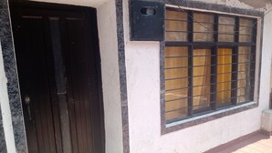A building entrance with a black door and a window with metal bars. - Barranquilla residencia norte (Cali)