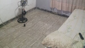A room with a bed, a television mounted on the wall, a standing fan, and a curtain. - Barranquilla residencia norte (Cali)
