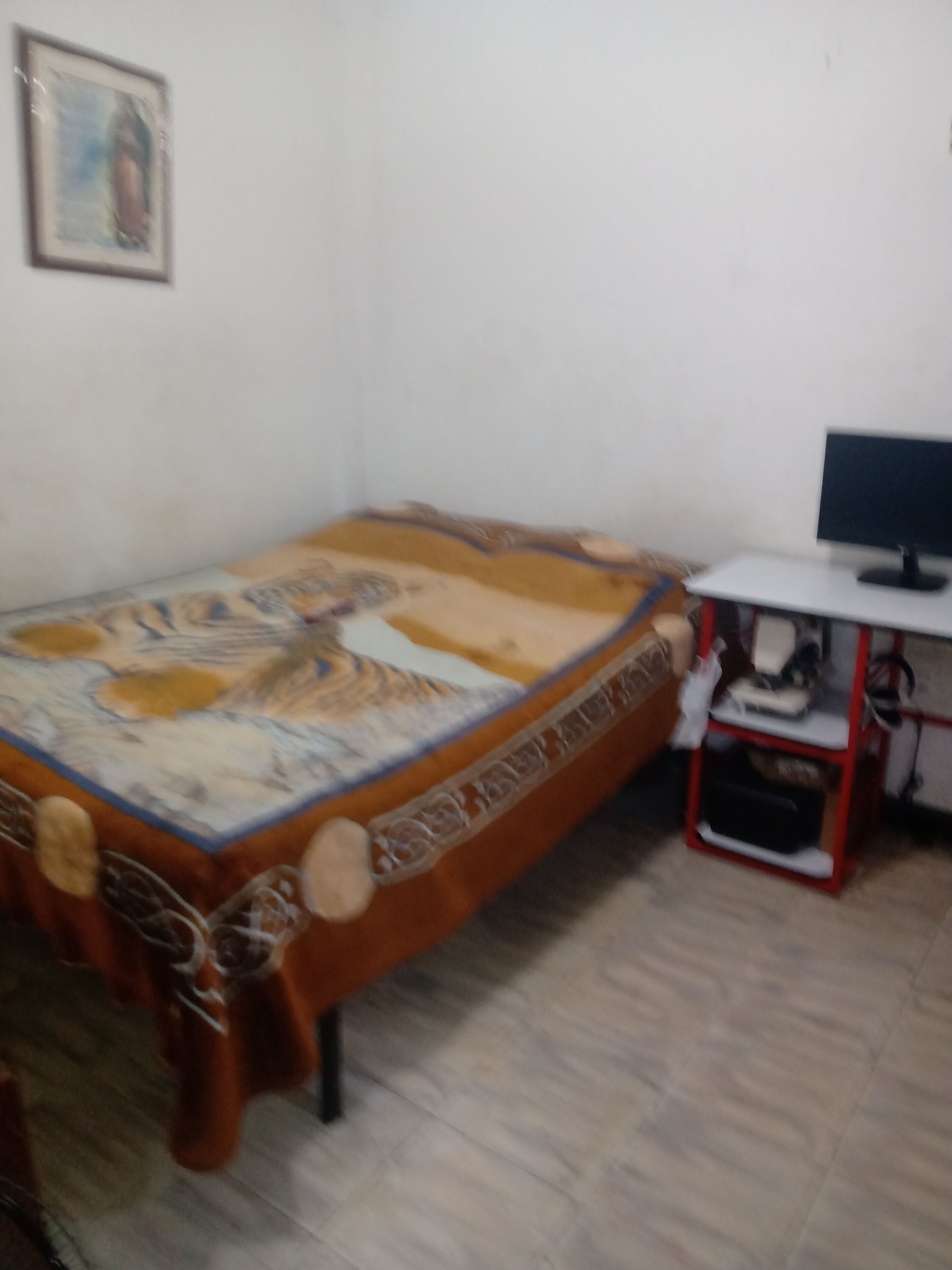 A bedroom with a bed, a desk, and a chair.