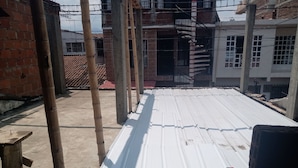 A rooftop with metal roofing, bamboo poles, and a partially constructed building with brick walls and a tiled roof. - Barranquilla residencia norte (Cali)