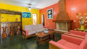 A living room with a sofa, armchairs, a coffee table, a fireplace, and a kitchen area with bar stools. - Chácara Master - O Melhor de Guararema (Guararema)