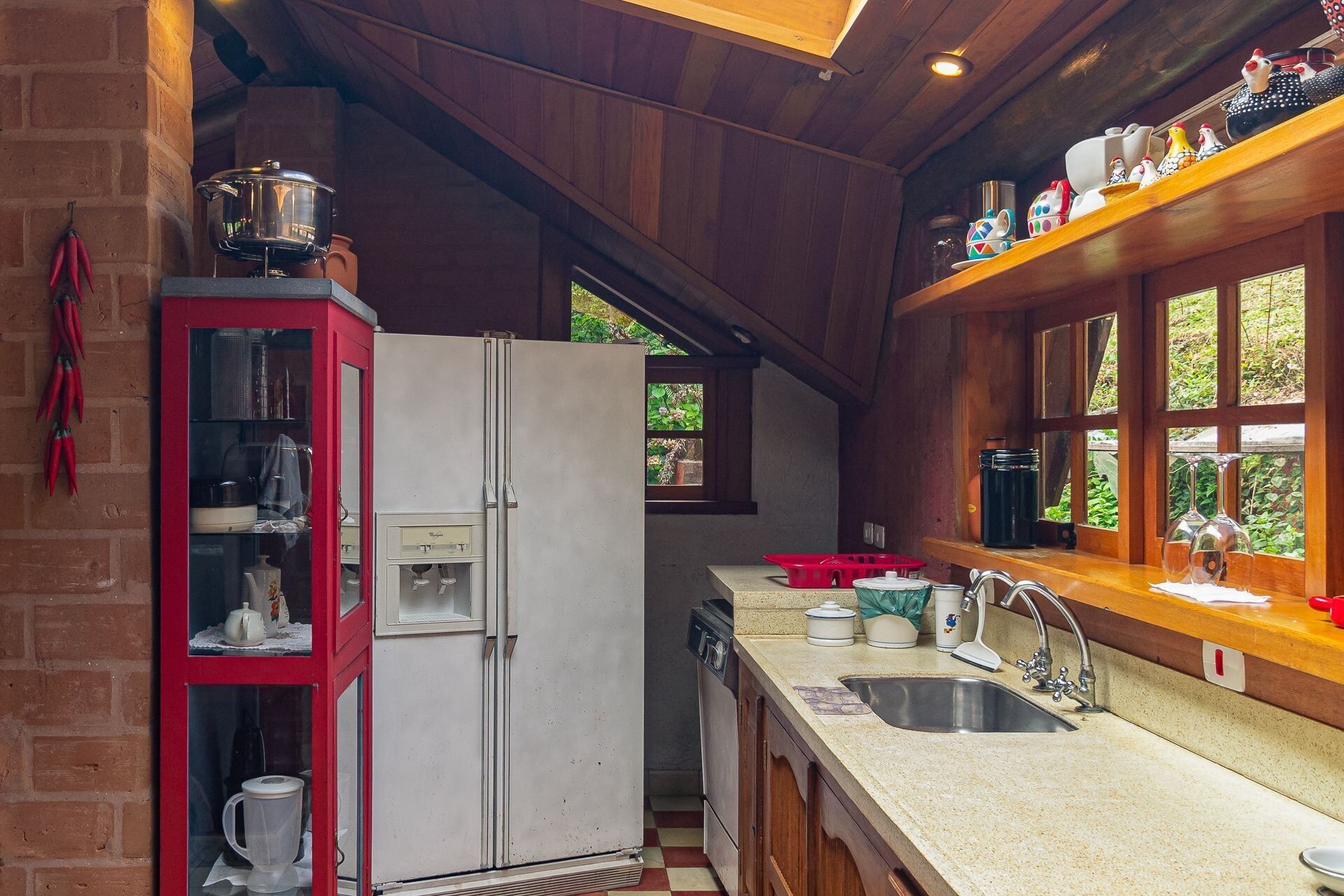 A kitchen with a white refrigerator, a red cabinet, and a window overlooking greenery.